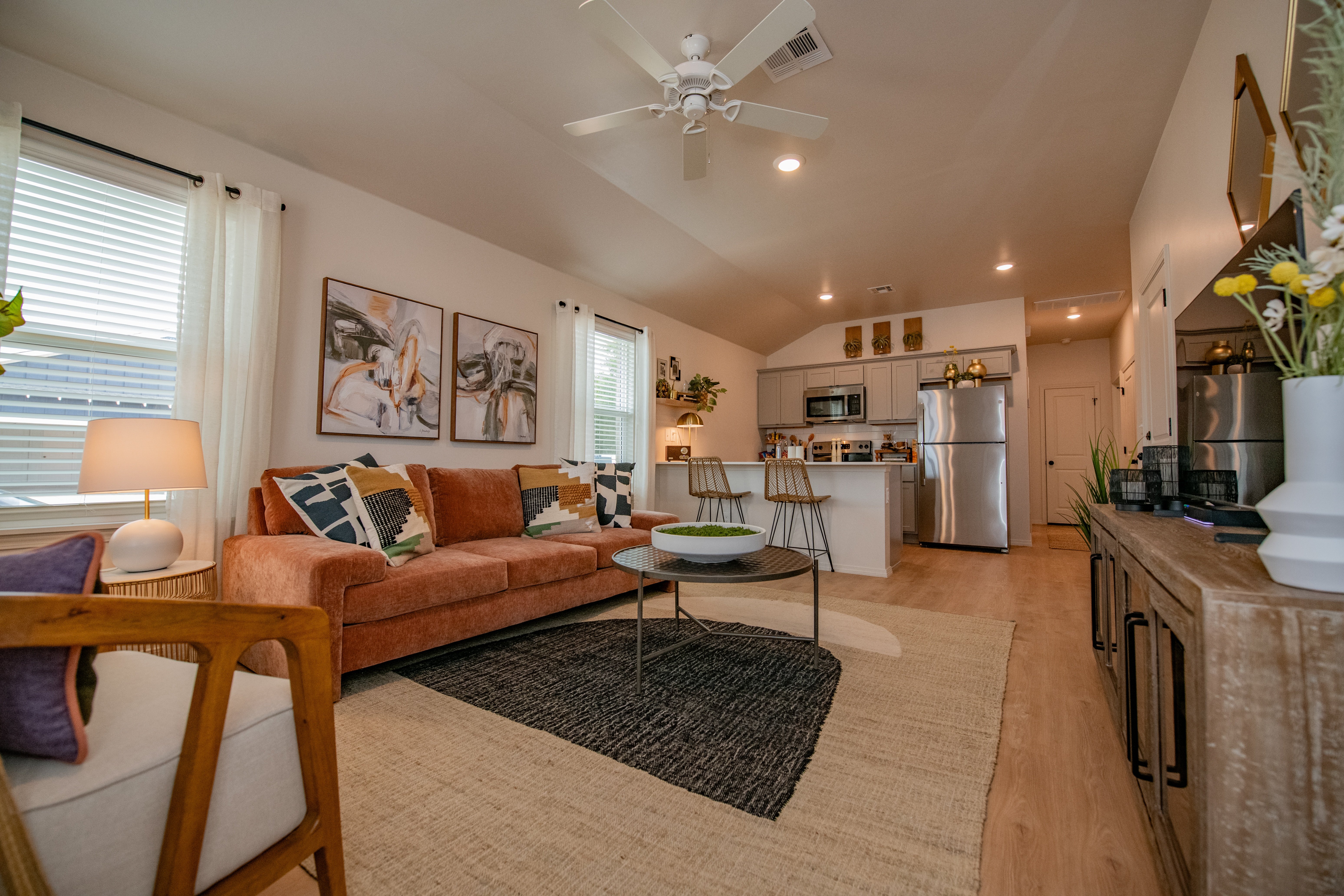 A living room with a couch, a coffee table, and a ceiling fan.